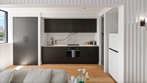 A modern kitchen with dark cabinets, a marble backsplash, and a built-in oven. - Bright 2-Bed Apt with Spectacular Bridge Views (Glebe)