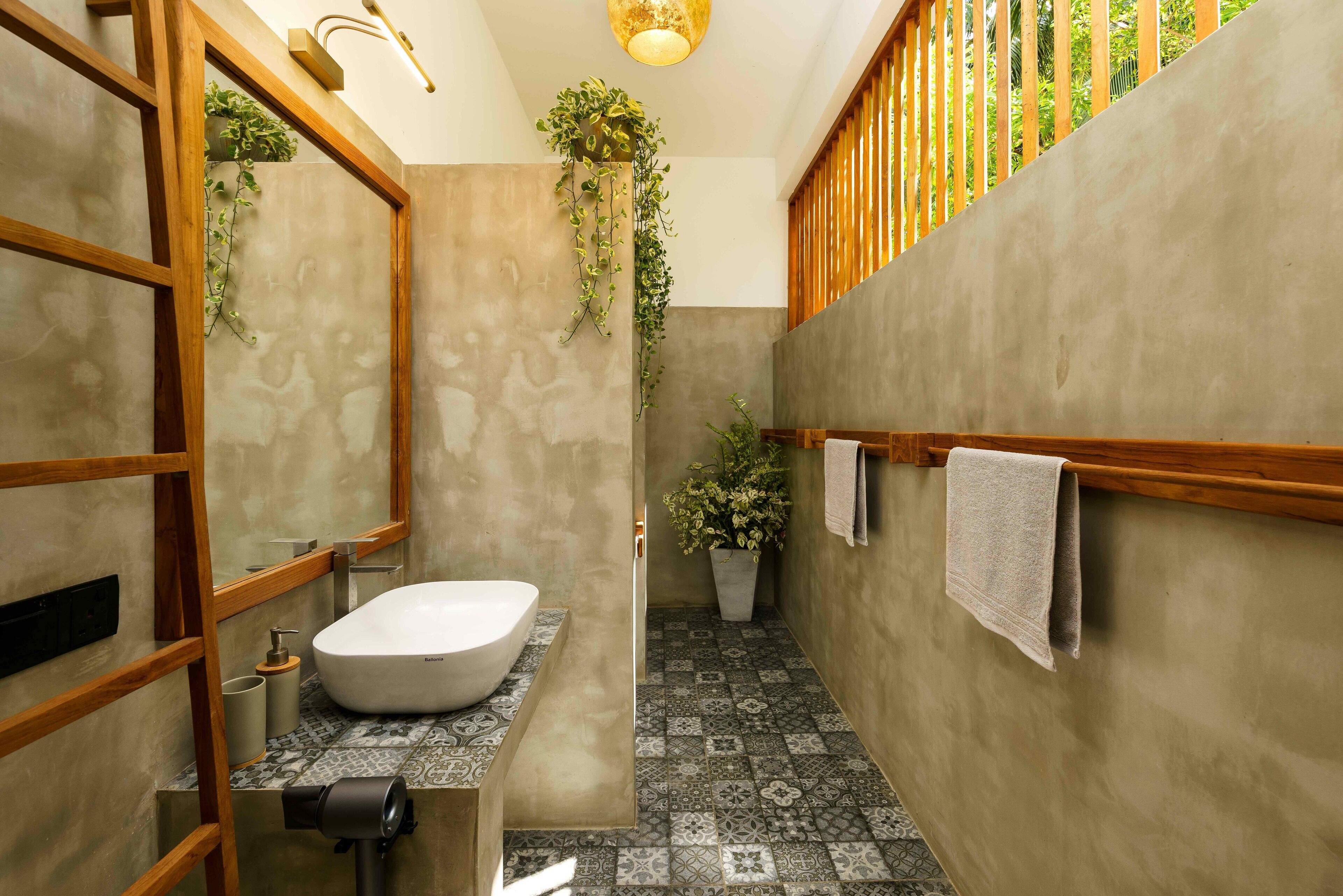 A modern bathroom with a freestanding bathtub, a wooden-framed mirror, and a potted plant.