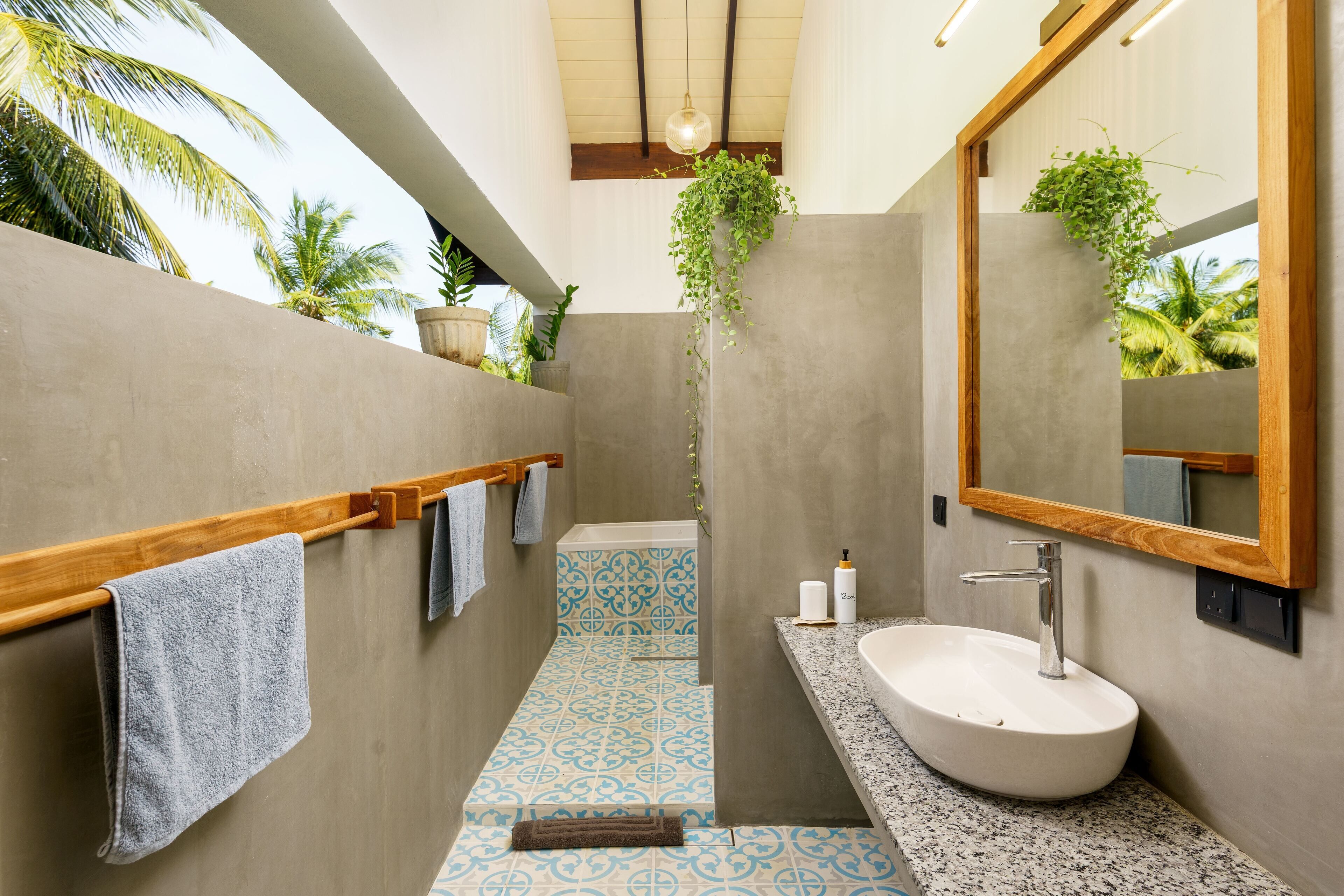 A modern bathroom with a large sink, wooden towel rack, and a mirror.