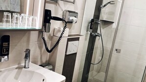 A modern bathroom with a sink, toilet, and glass-enclosed shower. - Hotel Paintner (Germering)