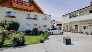 A hotel with a traditional European architectural style, featuring a wooden balcony with flower boxes, a paved driveway, and a car parked in front. - Hotel Paintner (Germering)