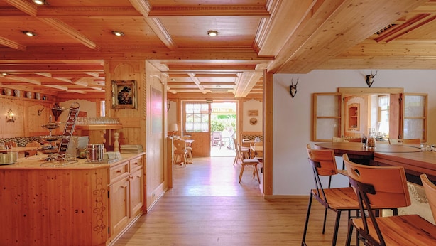A wooden interior with a kitchen, dining area, and bar. - Hotel Paintner (Germering)