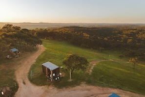 Propiedad rural con una edificación, un camino de tierra y árboles circundantes.