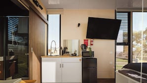 A compact kitchen with a built-in microwave, a sink, and a small refrigerator.