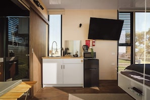 Cocina compacta con microondas incorporado, lavamanos y refrigerador pequeño.