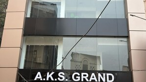 Egy épület homlokzata, amelyen az „A.K.S. GRAND” felirat látható, jelezve, hogy egy szálloda vagy kereskedelmi épület található benne.
