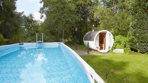 A swimming pool with a white deck and a small wooden structure in the background. - Spacious Holiday Home, Pool, Sauna, Whirlpool (Choczewo)