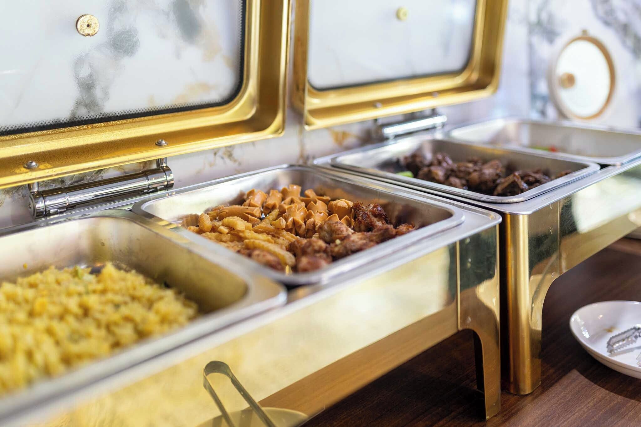 A buffet with various food options including pasta, meats, and rice.