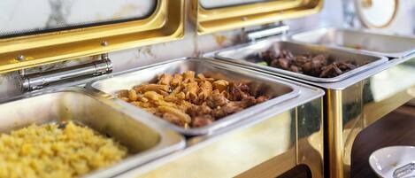 A buffet with various food options including pasta, meats, and rice.