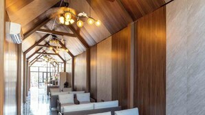 A modern hotel lobby with a high ceiling, wooden paneling, and a row of seating areas. - Champa Phan Boutique Hotel (Vientiane)