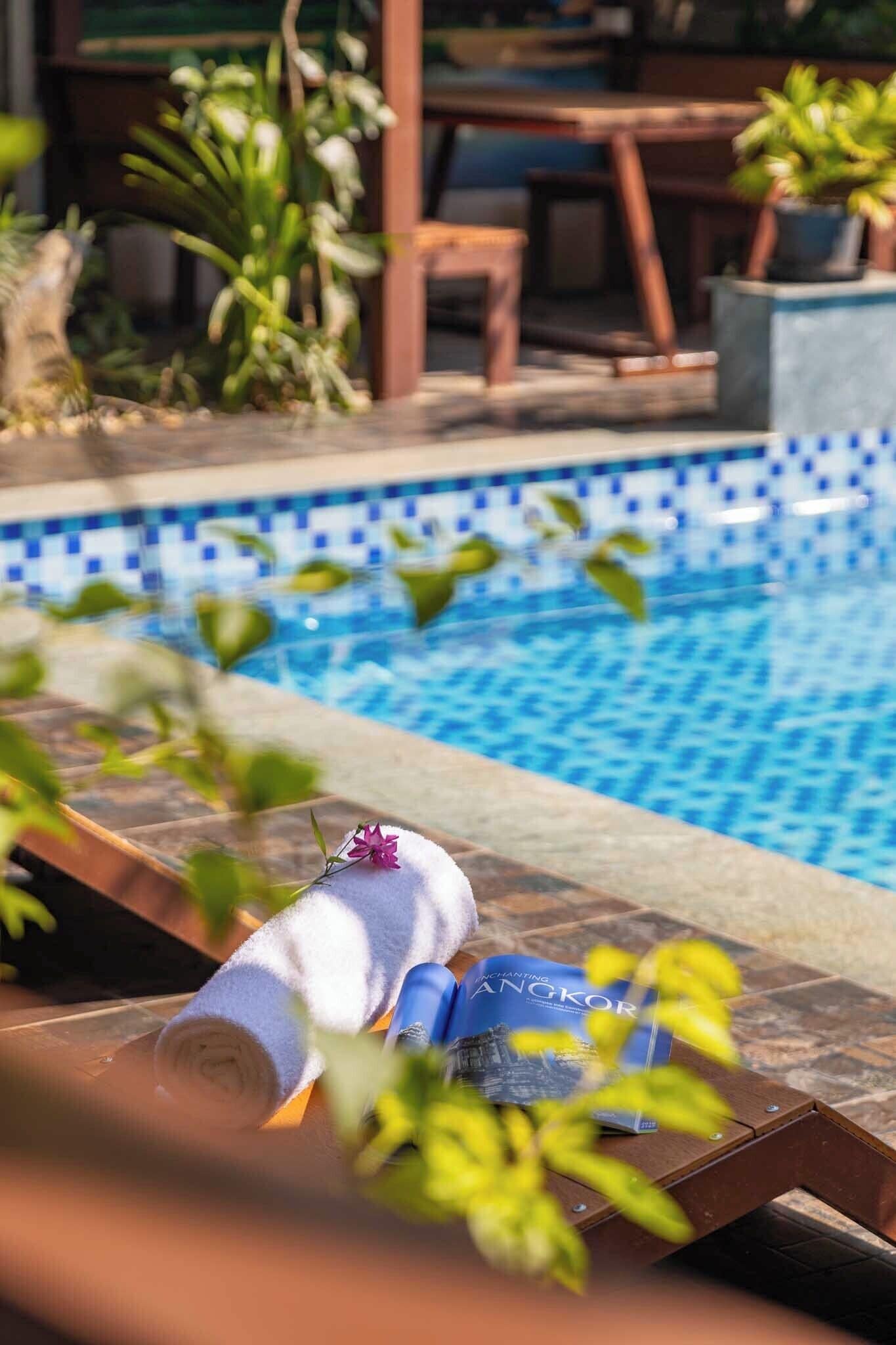 A poolside area with a towel, a book, and a chair.