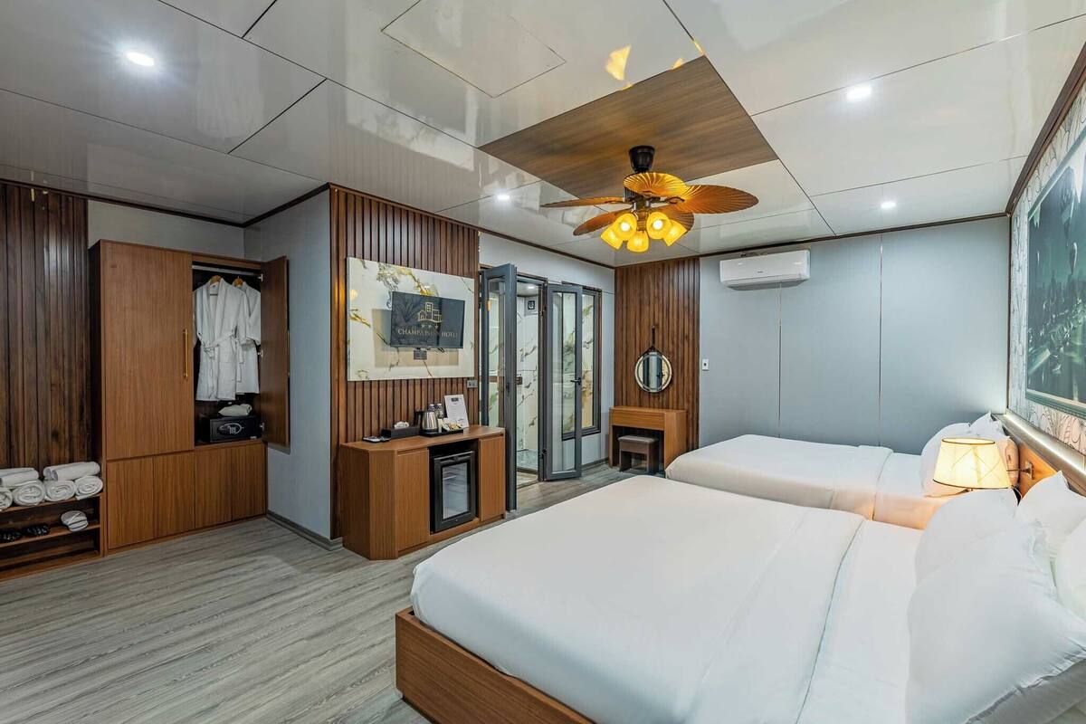 Una habitación de hotel moderna con dos camas, un armario, un escritorio y un ventilador de techo.