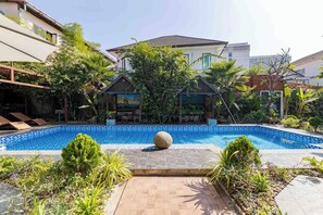 A swimming pool with a tiled edge, surrounded by greenery and a small gazebo. - Champa Phan Boutique Hotel (Vientiane)