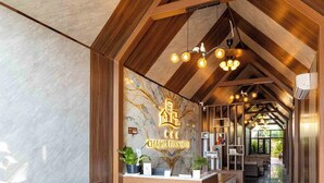 Un hall d’hôtel moderne avec un comptoir d’accueil en bois, un canapé moelleux de couleur marron et un sol en marbre.