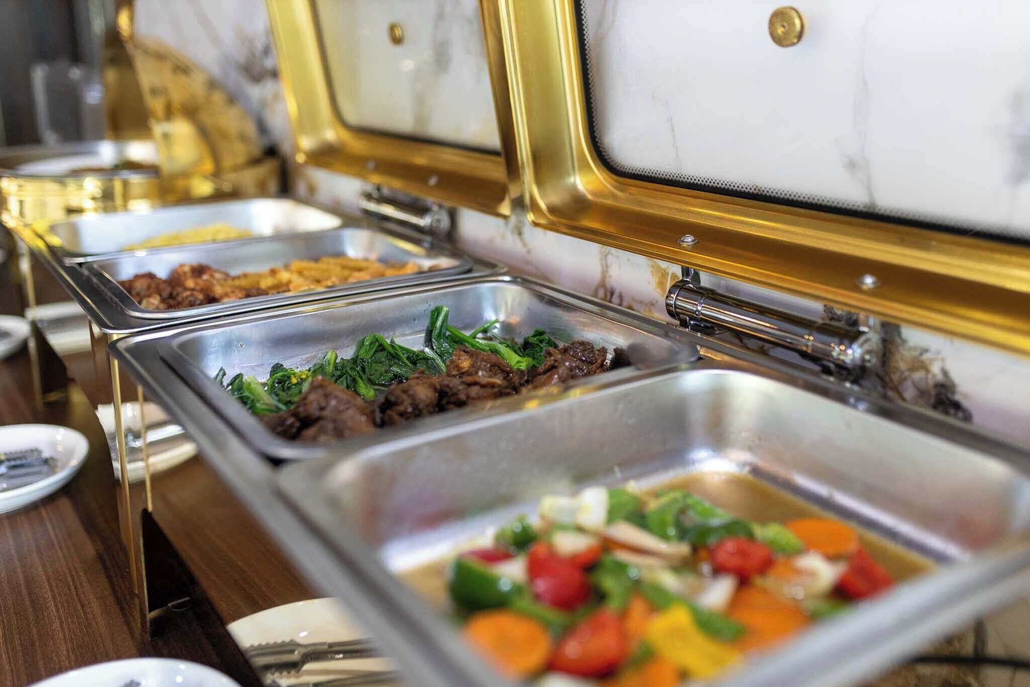 Ein Buffet mit verschiedenen Speisen, darunter Fleisch, Gemüse und Salate.