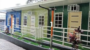 Une rangée de bâtiments aux couleurs vives, chacun ayant une couleur de porte différente, et une clôture blanche.
