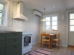 Eine Küche mit Herd, einem Fenster und einem Essbereich mit Stühlen.