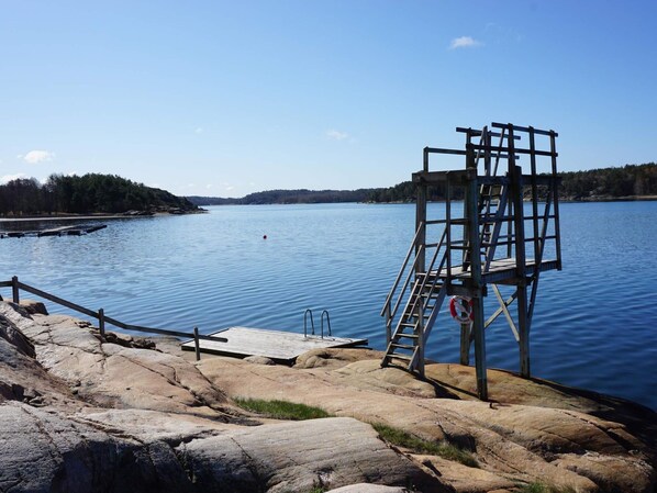 A clear view of a rocky shoreline with a wooden dock and a lifebuoy attached to a metal structure. - 4 Person Holiday Home in Tanumshede (Tanum)