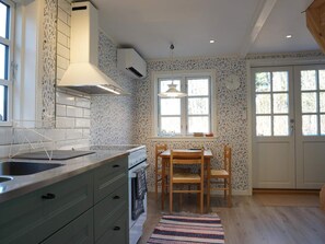 Ett kök med ett matbord, stolar, en hängande lampa och ett fönster med utsikt.