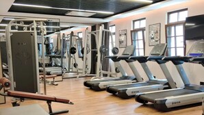Ein Fitnessstudio mit Laufbändern, Kraftgeräten und einer Bank.