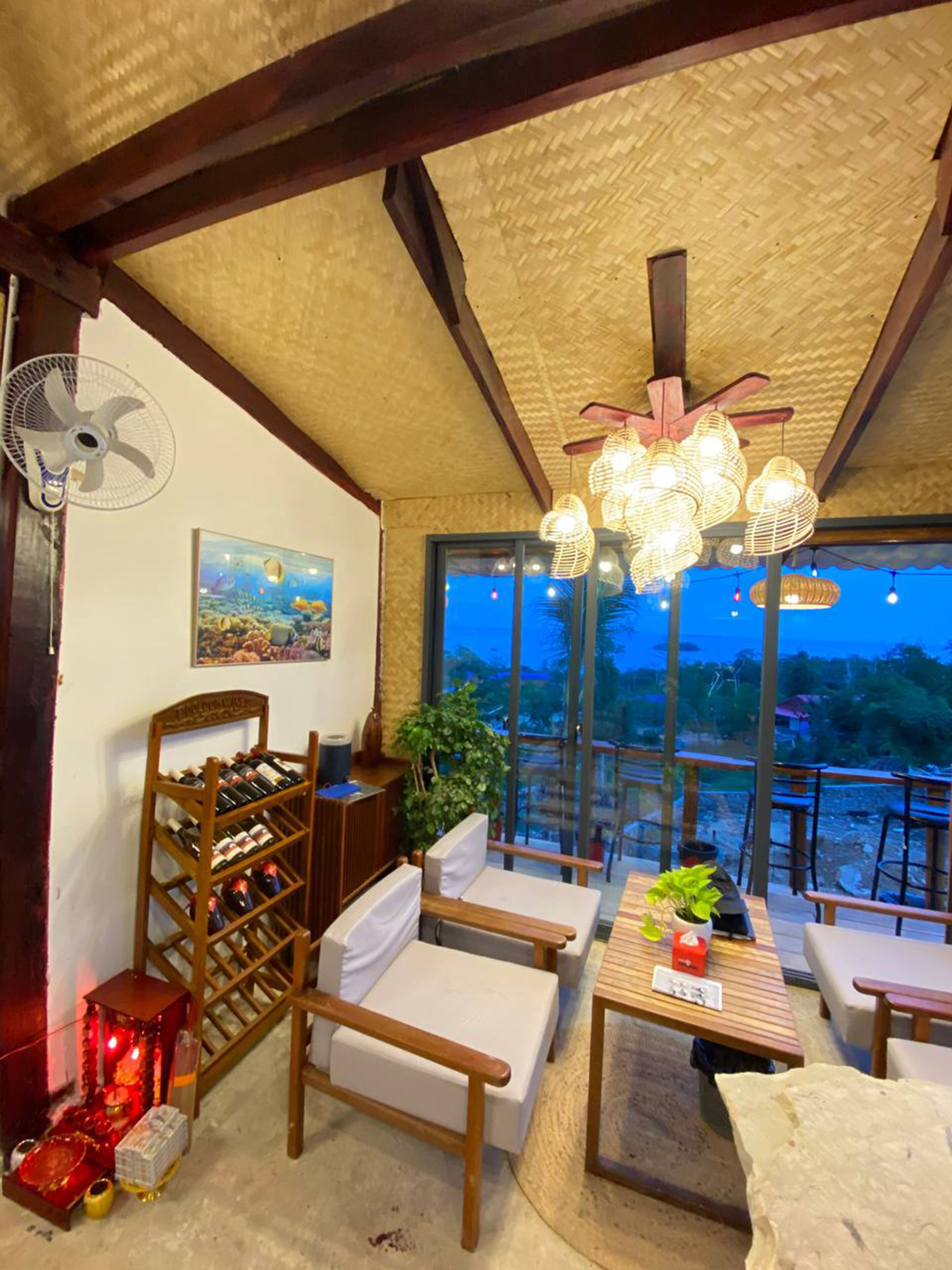 Una habitación acogedora con un botellero de madera, asientos cómodos, un ventilador y vistas al exterior.