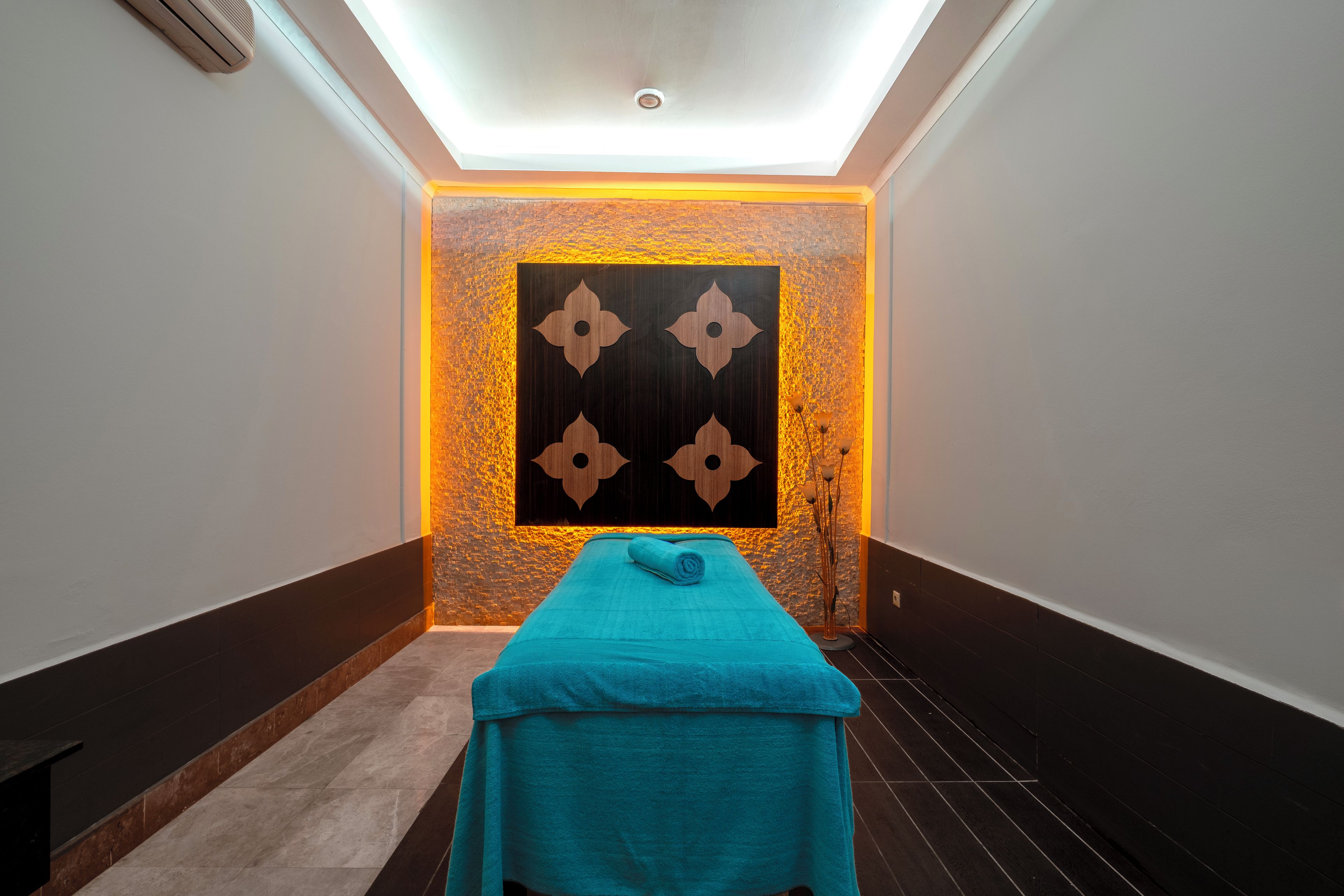 Un cuarto de spa con una camilla de masaje, una pared con un diseño geométrico y una pared con textura.