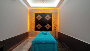 Un cuarto de spa con una camilla de masaje, una pared con un diseño geométrico y una pared con textura.