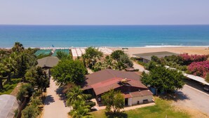 A coastal property with a beach, a pool, and a house with a red roof. - Solivia Hotel (Konaklı)