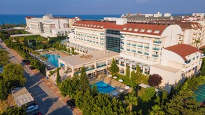 A hotel with multiple swimming pools, a large central building, and a view of the sea. - Solivia Hotel (Konaklı)