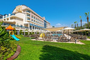 A resort with a swimming pool, lounge chairs, and a children's play area. - Solivia Hotel (Konaklı)