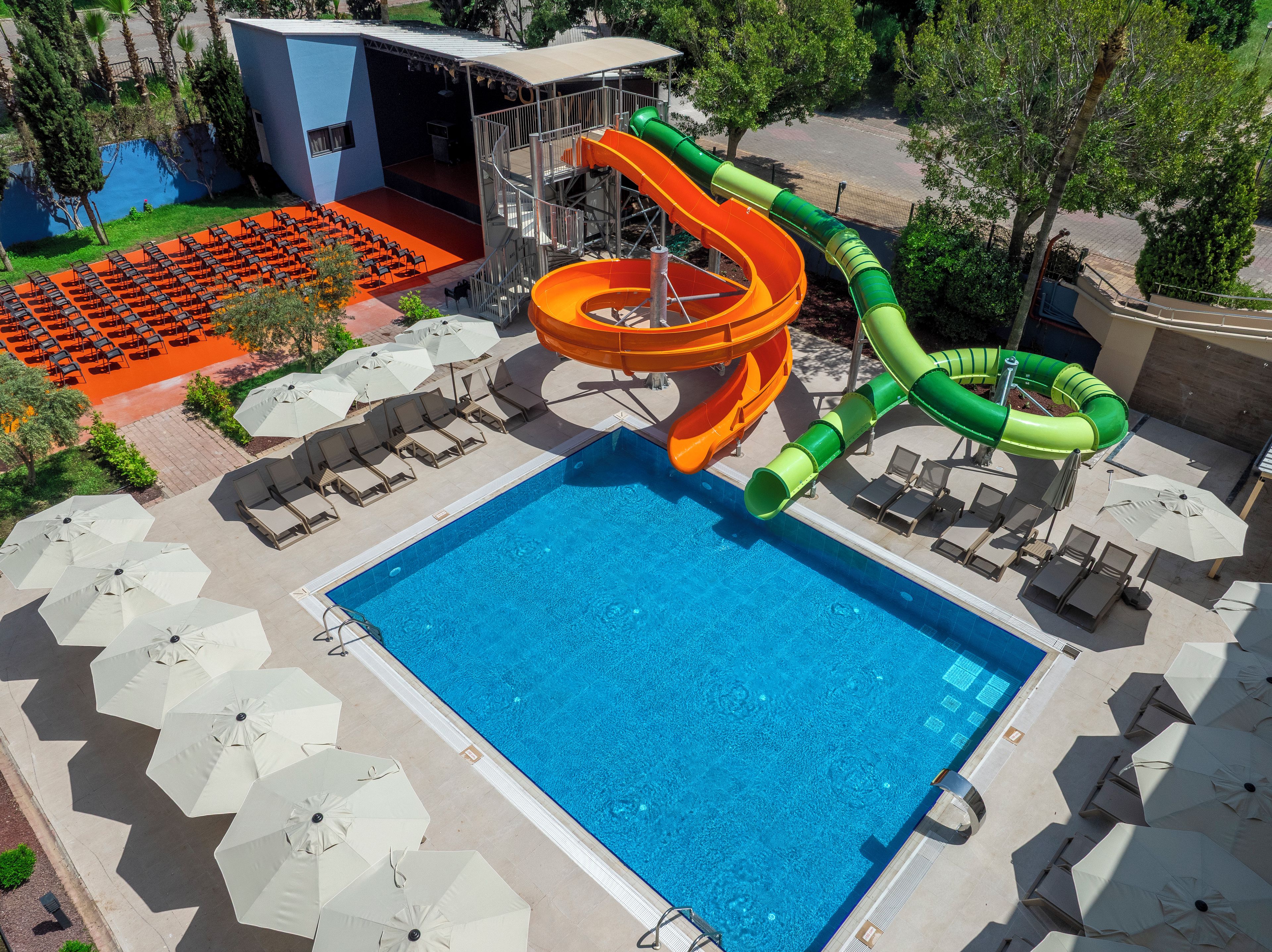 A pool with slides, lounge chairs, and umbrellas.
