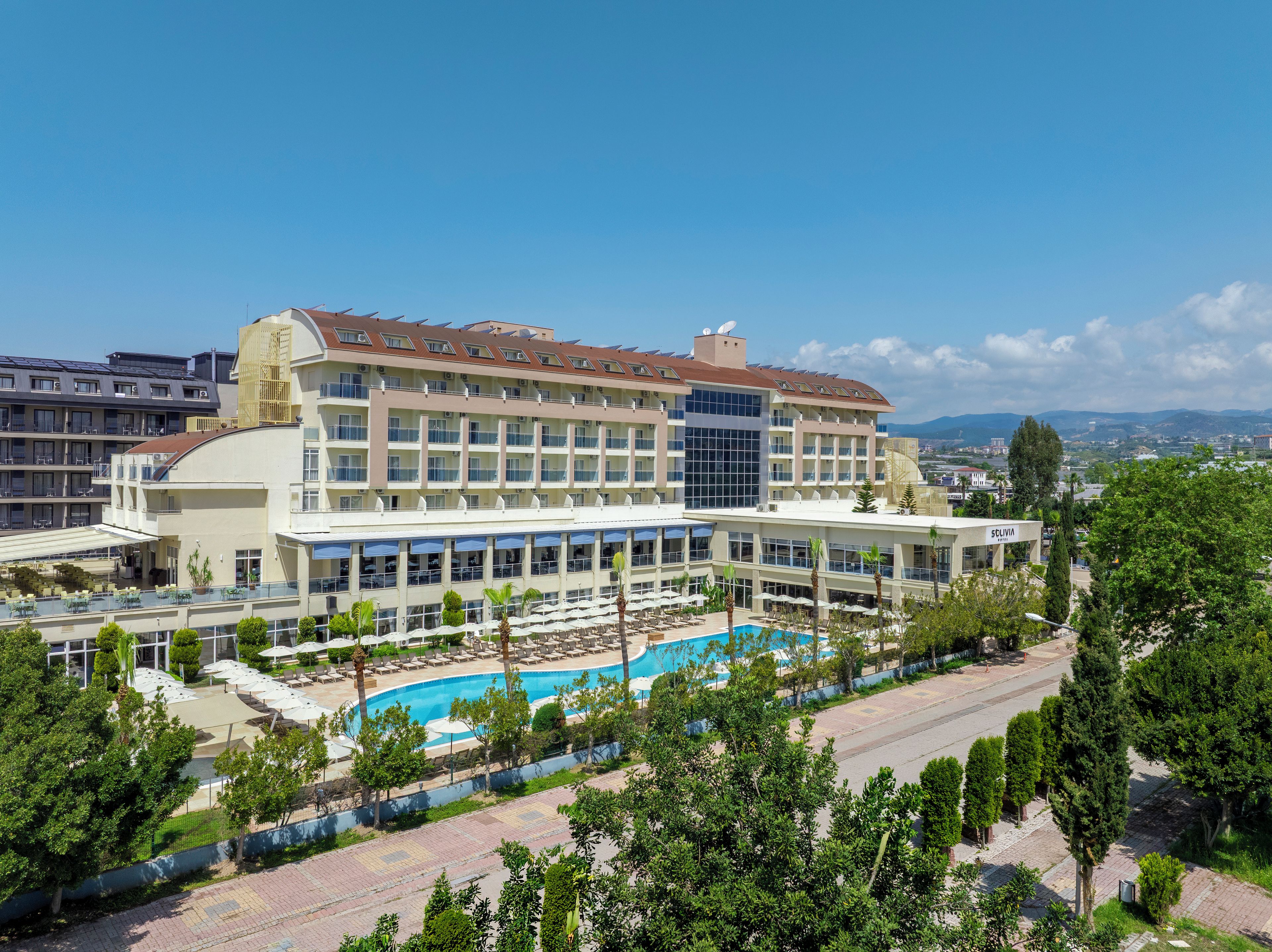 Un hotel con piscina, varios balcones y vistas de la ciudad circundante.