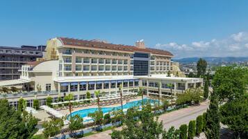 Un hotel con piscina, varios balcones y vistas de la ciudad circundante.