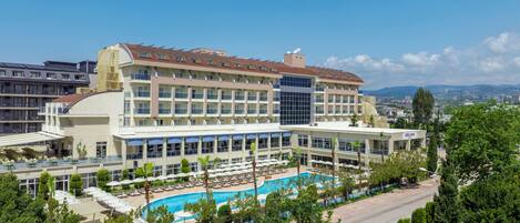 Um hotel com piscina, várias varandas e vista para a paisagem urbana ao redor.