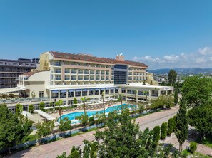 A hotel with a swimming pool, multiple balconies, and a view of the surrounding cityscape. - Solivia Hotel (Konaklı)