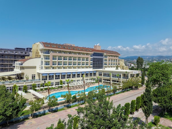 A hotel with a swimming pool, multiple balconies, and a view of the surrounding cityscape.