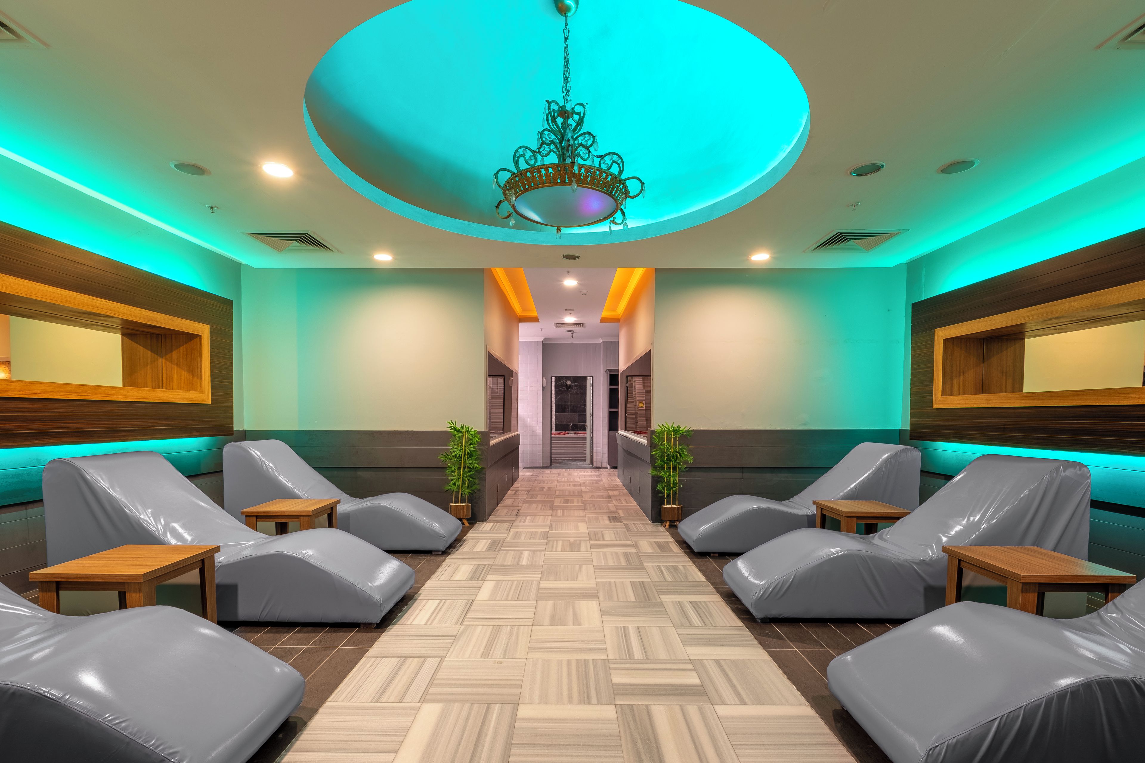Un área de spa con sillones de masaje, suelo de madera y una lámpara central.