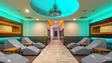 Un área de spa con sillones de masaje, suelo de madera y una lámpara central.