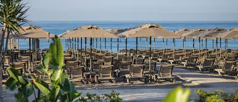 A beachside seating area with rows of chairs and umbrellas, overlooking the sea.