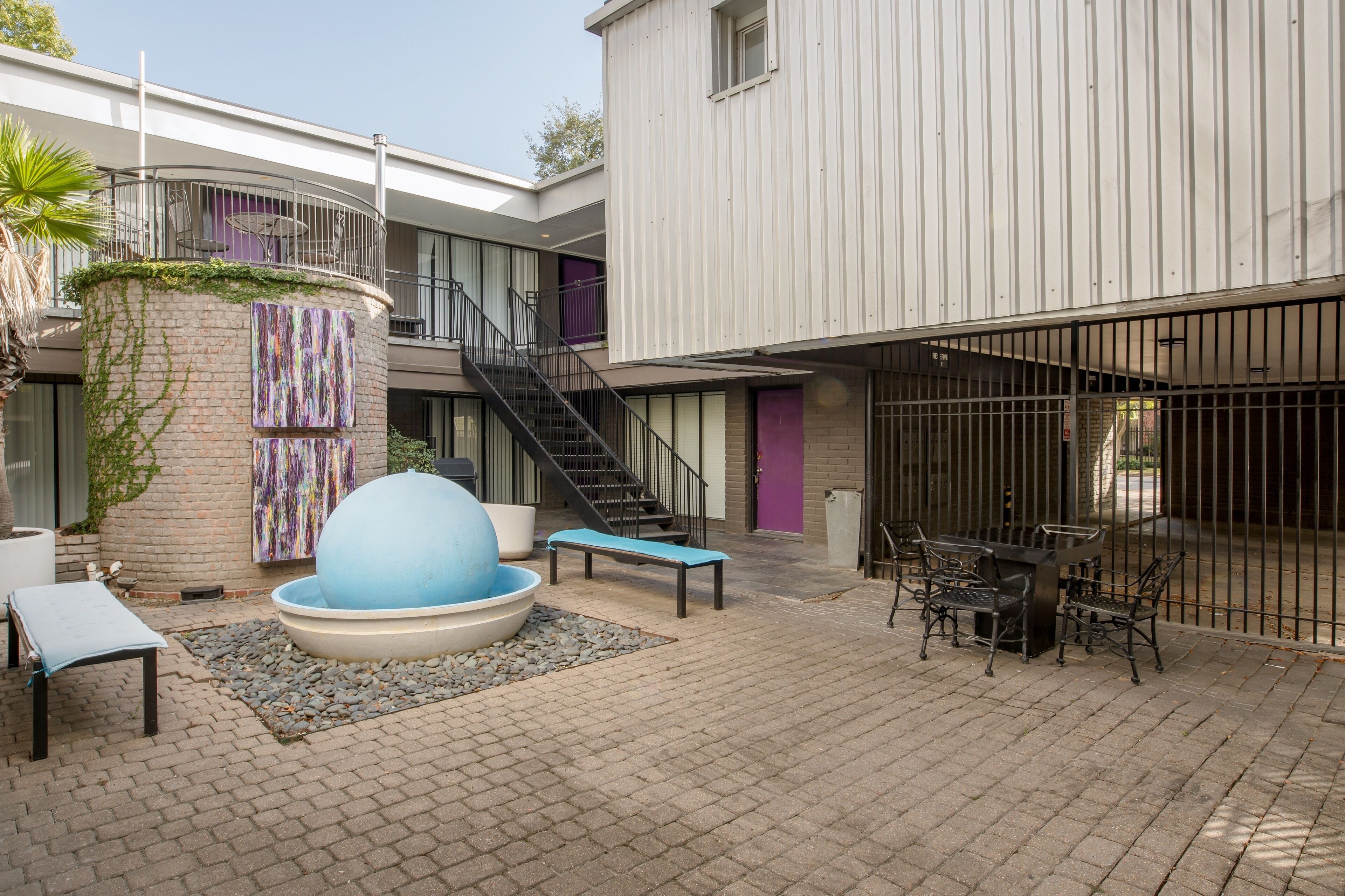 A courtyard with a blue spherical water feature, a staircase, and outdoor seating.