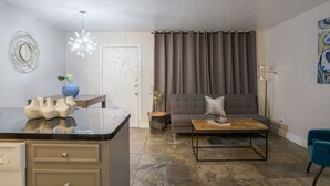 Ett modernt vardagsrum med en soffa, ett soffbord och en matplats med en köksö.
