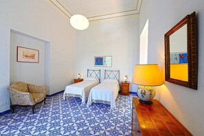 Een kamer met twee bedden, een stoel, een lamp en kunstwerken aan de wanden.