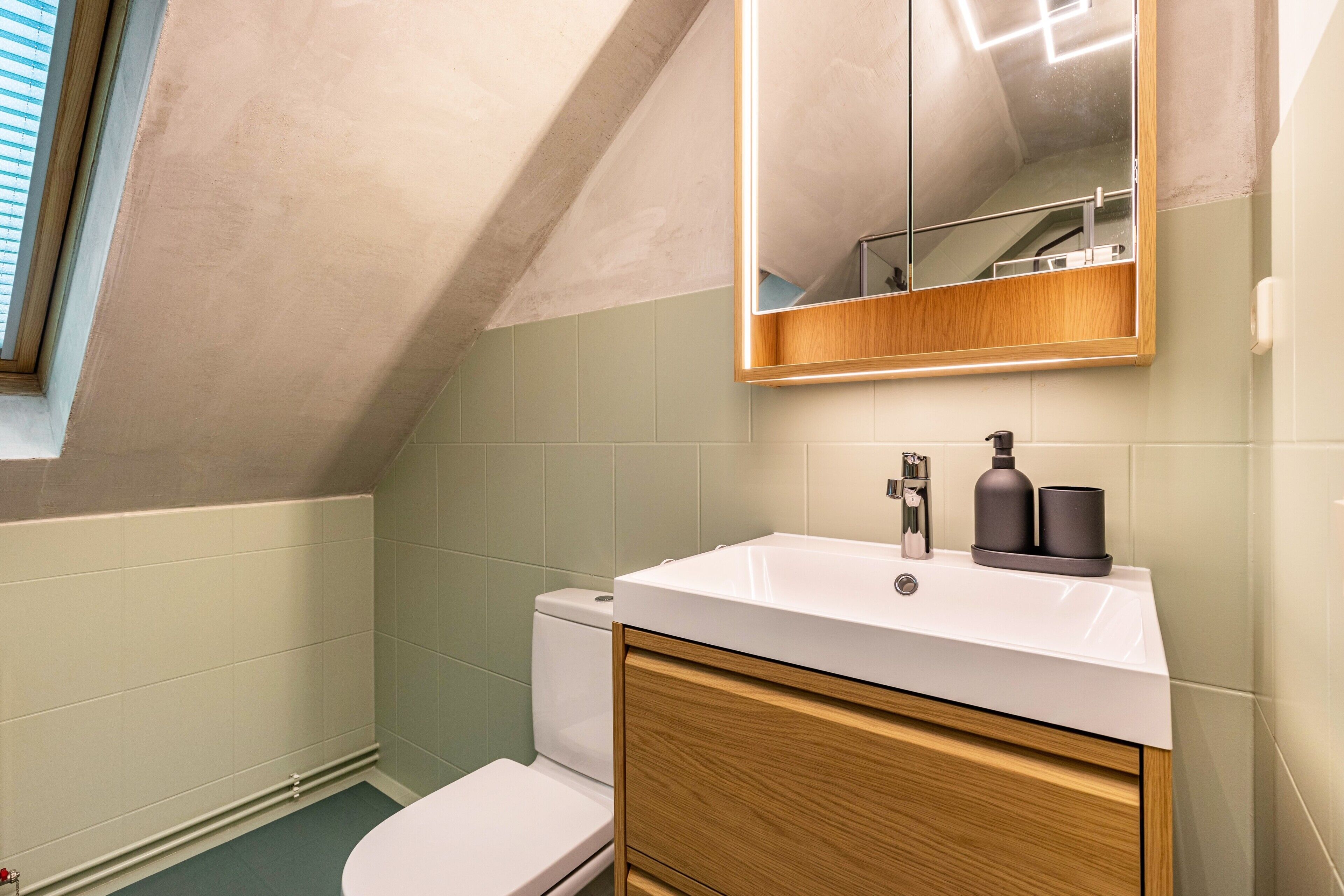 Un baño con lavamanos blanco, tocador de madera y un espejo encima.