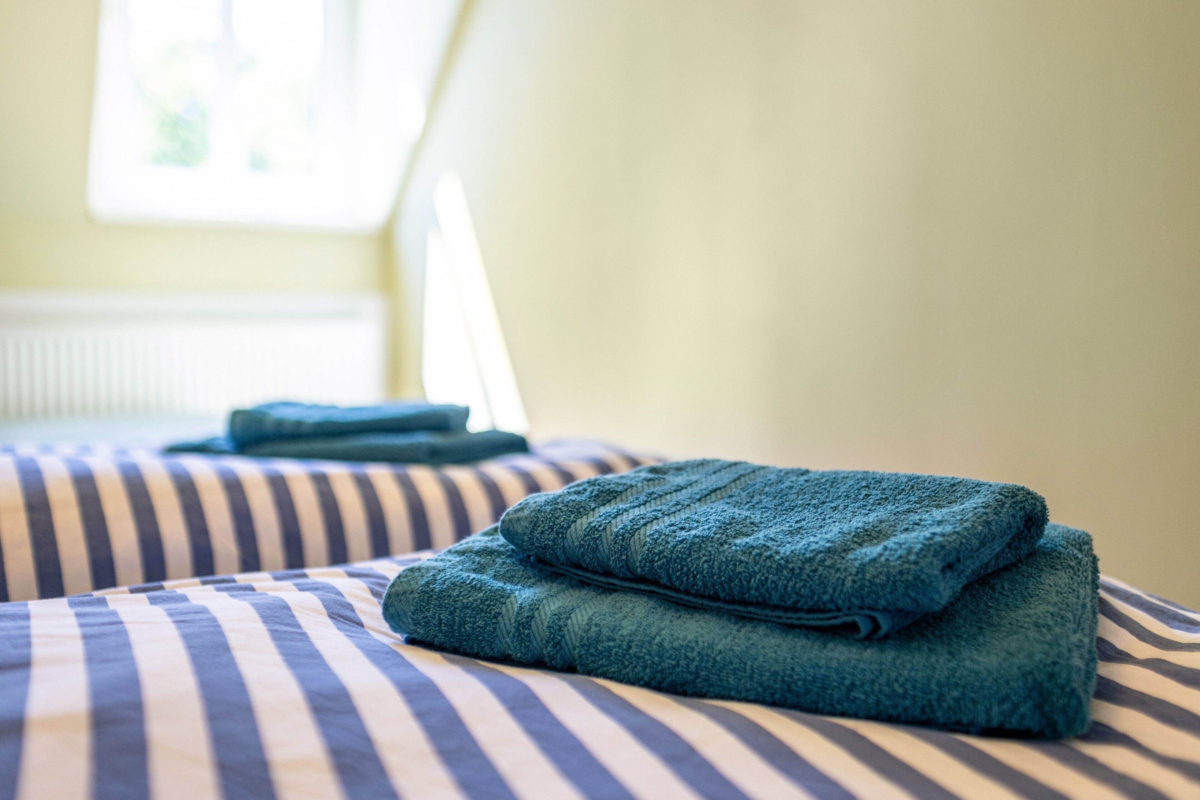 Ein Bett mit gestreifter Bettwäsche und gefalteten Handtüchern.