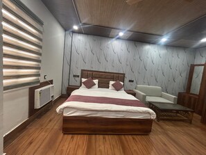 A modern bedroom with a wooden bed, a white sofa, and a wooden coffee table. - Hotel Shri Dauji Maharaj Palace (Mahaban)
