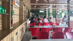 Un restaurant avec des murs lambrés, des chaises rouges et des tables.