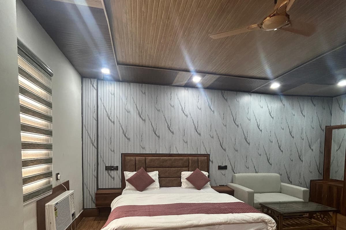 Une chambre avec un lit en bois, un ventilateur de plafond, une chaise blanche et une table de chevet.