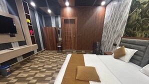 Une chambre d’hôtel avec un grand lit, une armoire en bois, un petit bureau et un téléviseur.