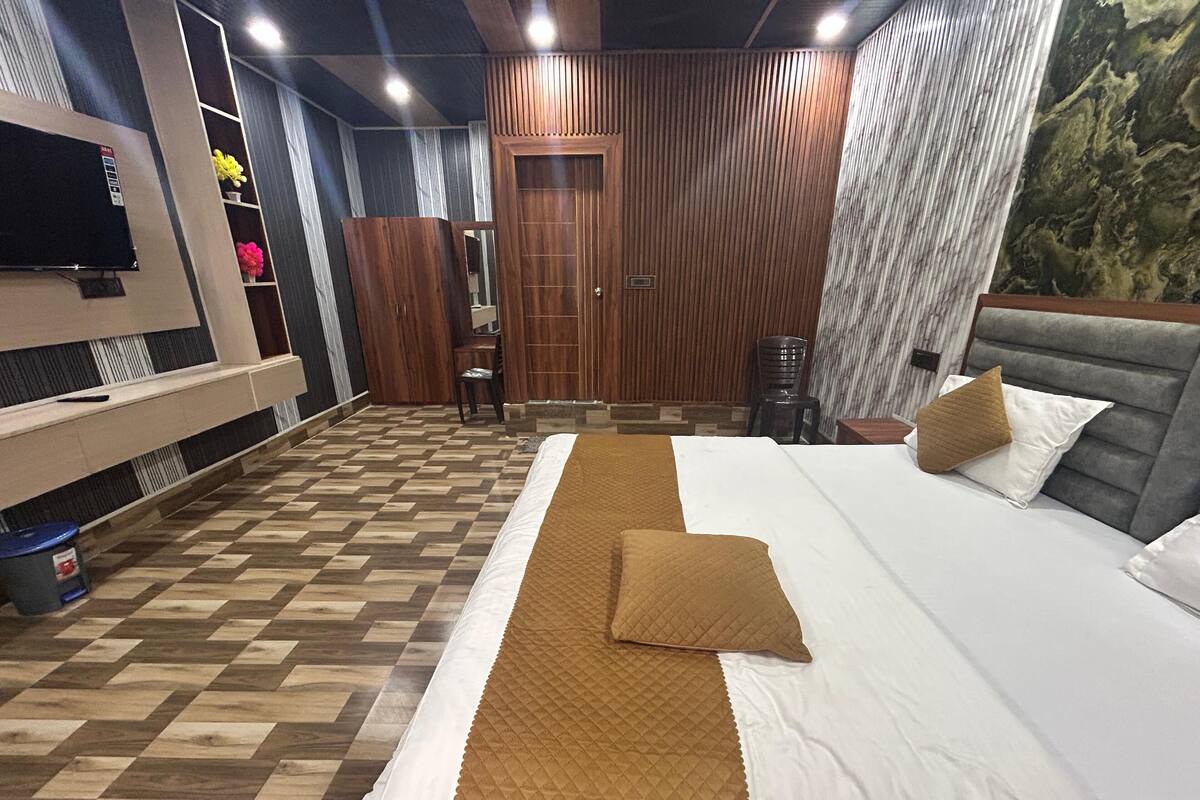 Une chambre d’hôtel avec un grand lit, une armoire en bois, un petit bureau et un téléviseur.