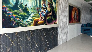 Un intérieur moderne agrémenté d’une grande fresque représentant une divinité jouant de la flûte, d’un mur à motifs et d’un espace détente avec des coussins bleus.